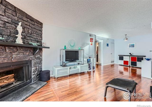 living room featuring a fireplace, hardwood / wood-style floors, and a textured ceiling