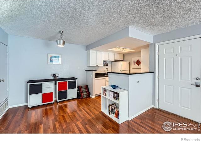 kitchen with dark hardwood / wood-style flooring, white appliances, white cabinetry, and a textured ceiling