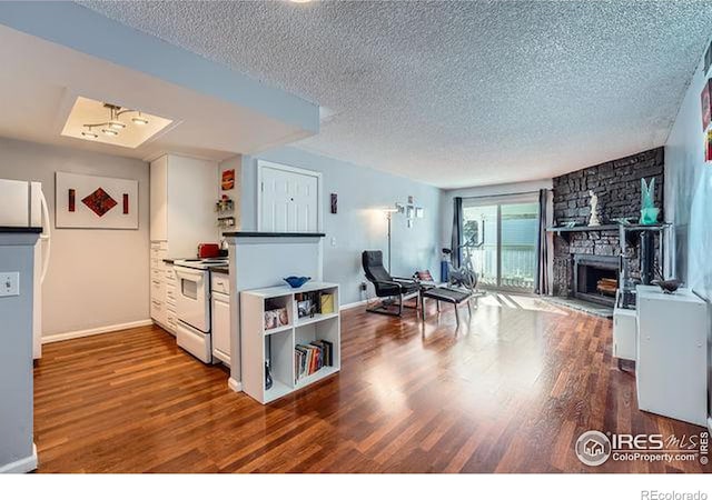 kitchen featuring dark hardwood / wood-style flooring, a textured ceiling, white range with electric cooktop, and a stone fireplace