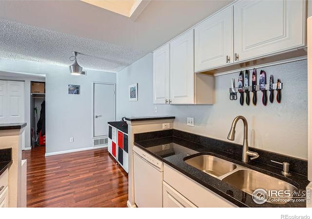 kitchen with sink, dark wood-type flooring, white dishwasher, a textured ceiling, and white cabinets