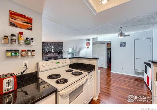 kitchen with electric range, dark hardwood / wood-style floors, white cabinets, and a textured ceiling