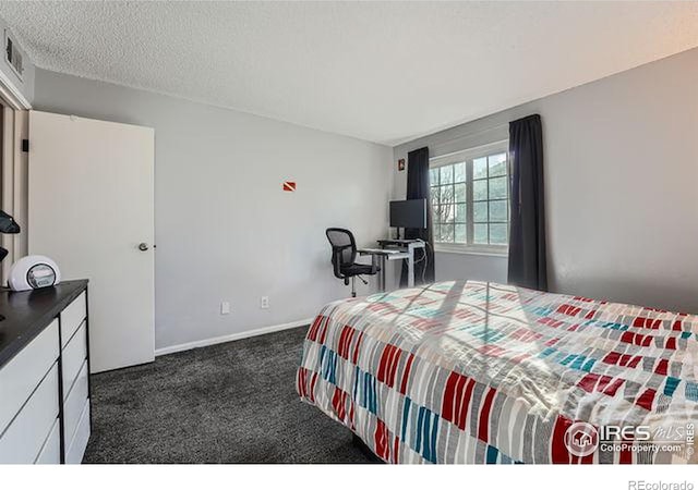 bedroom with dark carpet and a textured ceiling