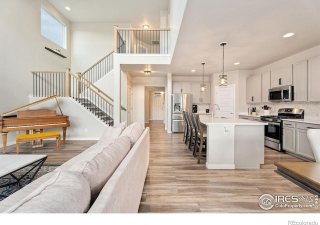 kitchen featuring decorative light fixtures, a center island with sink, white cabinets, and appliances with stainless steel finishes