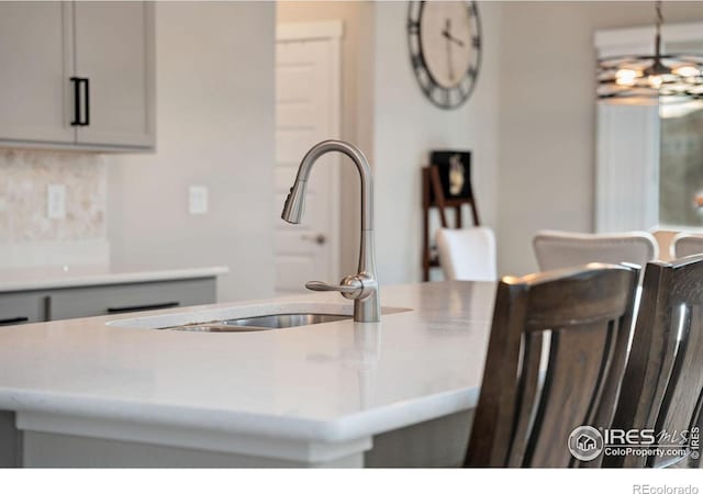 kitchen featuring sink, hanging light fixtures, a chandelier, and a center island with sink