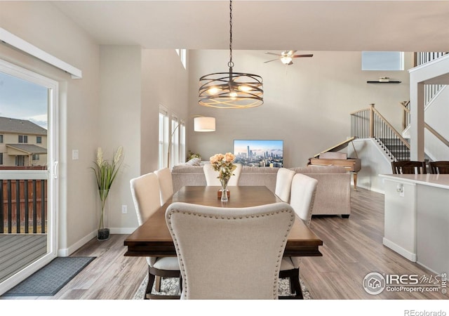 dining area with ceiling fan with notable chandelier and light hardwood / wood-style flooring