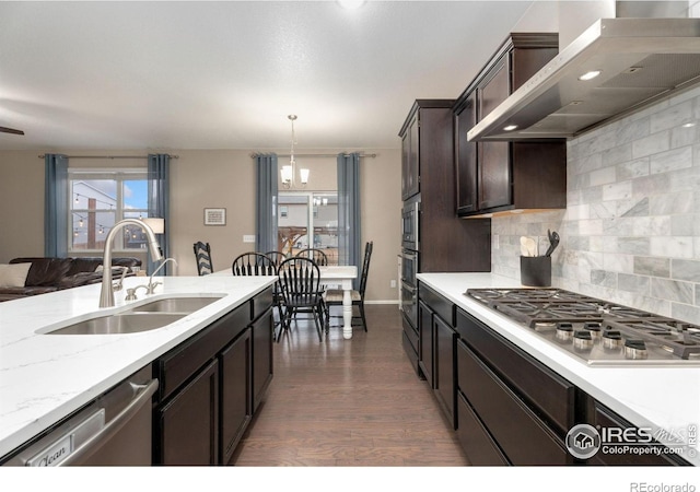 kitchen with decorative backsplash, stainless steel appliances, sink, wall chimney range hood, and hanging light fixtures