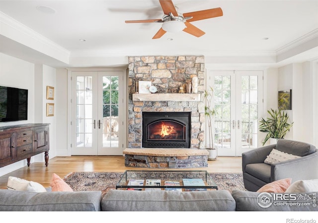 living room featuring a fireplace, a healthy amount of sunlight, light hardwood / wood-style flooring, and french doors