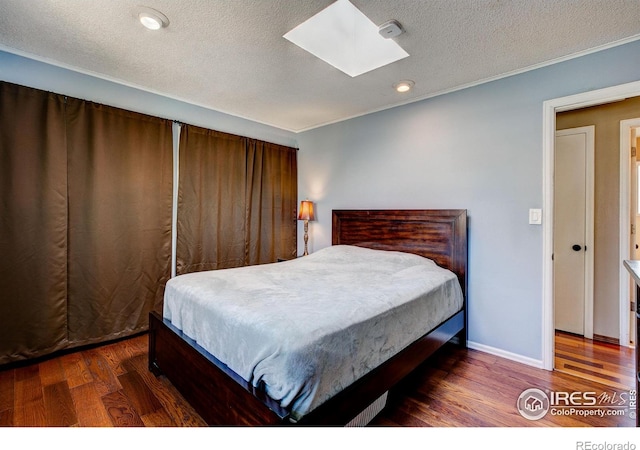 bedroom featuring a textured ceiling, a skylight, and dark hardwood / wood-style floors