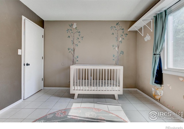 unfurnished bedroom with light tile patterned floors and a nursery area