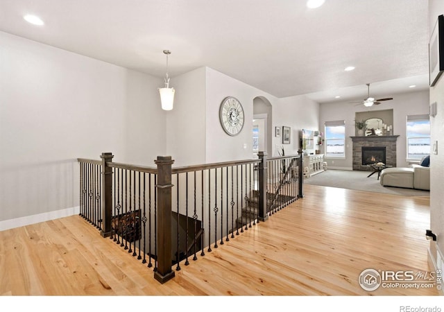 stairway featuring ceiling fan, a fireplace, and hardwood / wood-style flooring