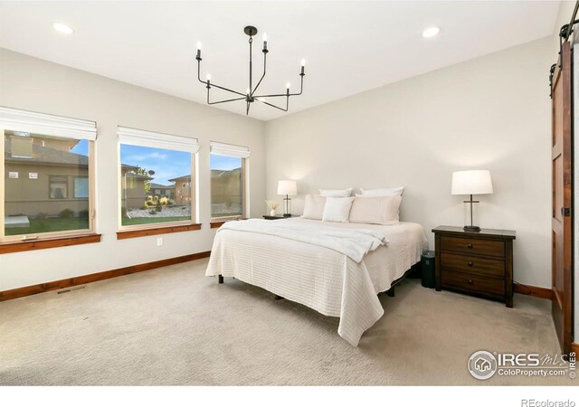 carpeted bedroom featuring an inviting chandelier and a barn door