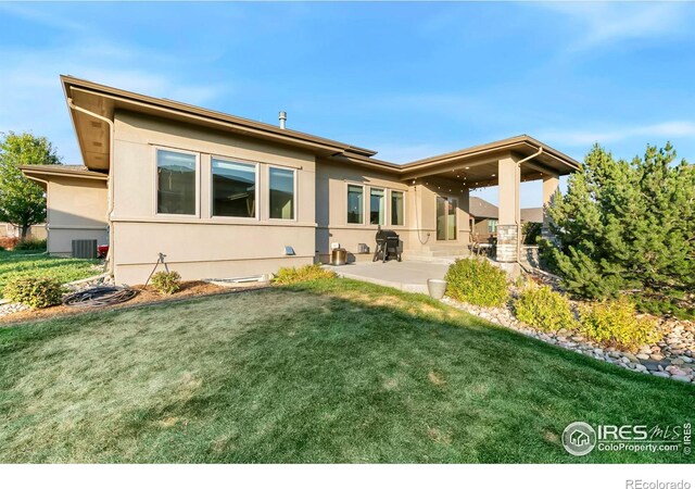 rear view of property with central air condition unit, a patio, and a lawn