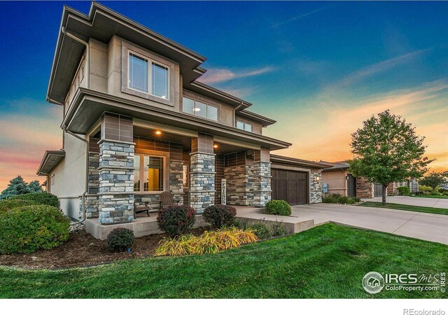 prairie-style home featuring a garage, a yard, and covered porch