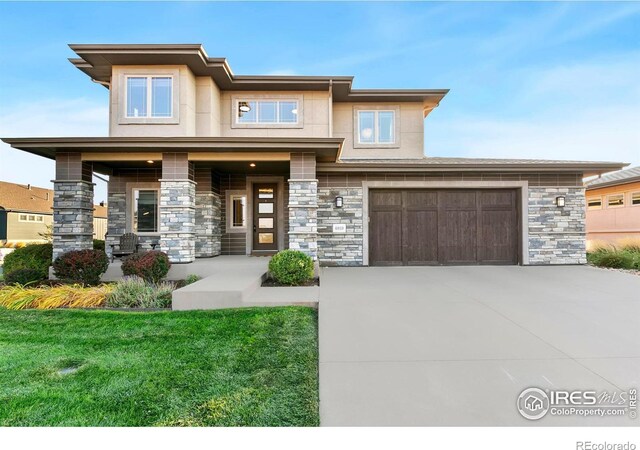 prairie-style home with covered porch, a front lawn, and a garage