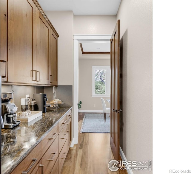 kitchen with dark stone countertops and light hardwood / wood-style flooring