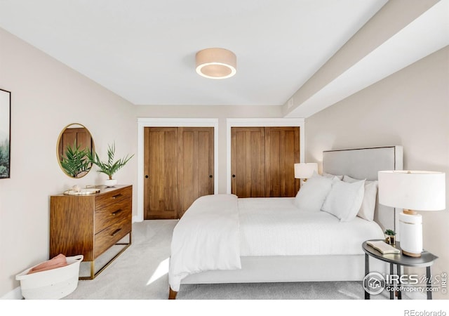 bedroom featuring two closets and light colored carpet