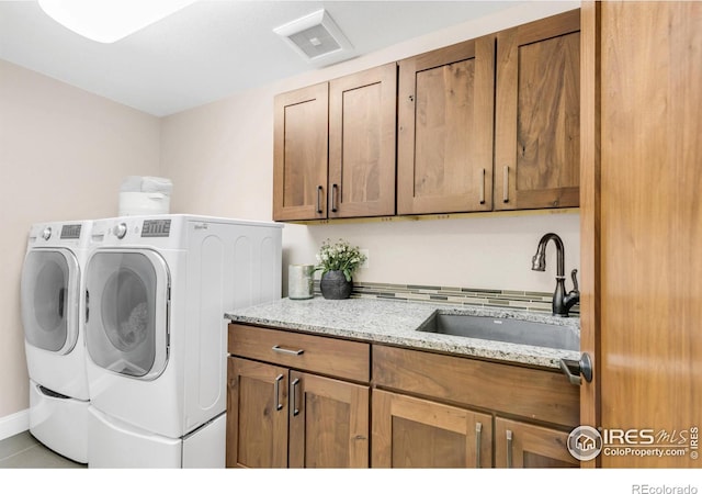 laundry room featuring washing machine and clothes dryer, sink, light tile patterned flooring, and cabinets