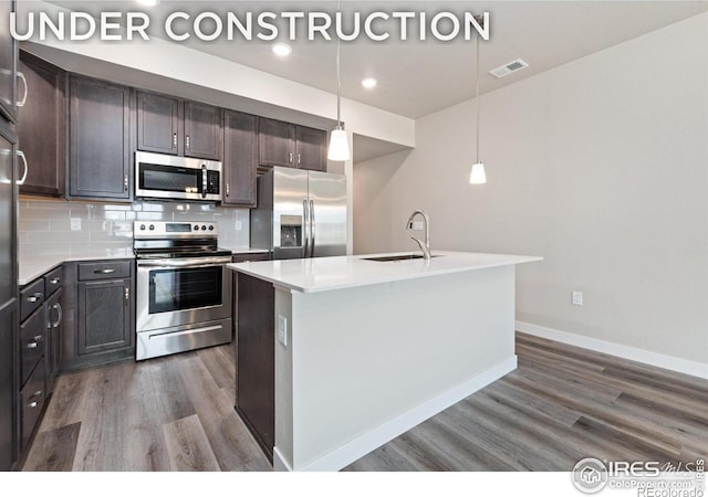410 High Point Dr Unit 104, Longmont, CO 80504 - kitchen featuring sink, appliances with stainless steel finishes, decorative backsplash, a center island with sink, and decorative light fixtures