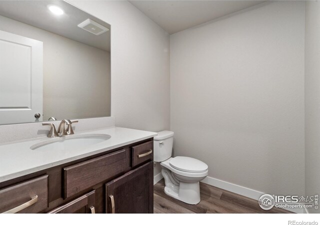 410 High Point Dr Unit 104, Longmont, CO 80504 - bathroom featuring hardwood / wood-style flooring, vanity, and toilet