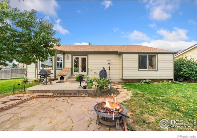 back of property featuring french doors, a patio, an outdoor fire pit, and a yard