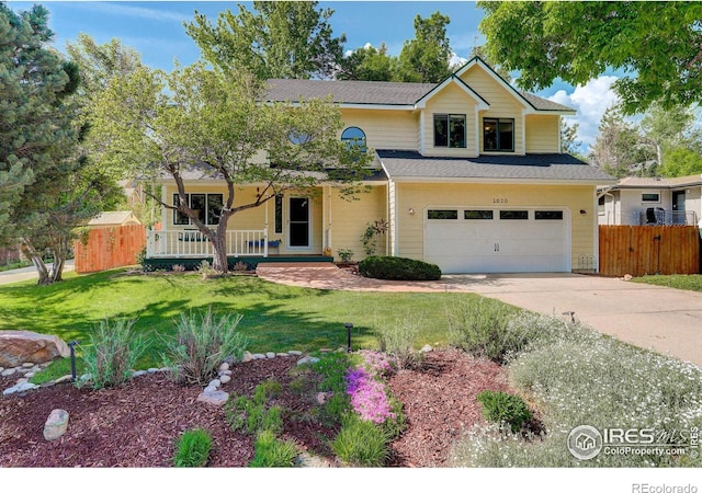 traditional home with a porch, fence, concrete driveway, a front yard, and a garage