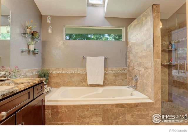 bathroom with vanity and tiled bath