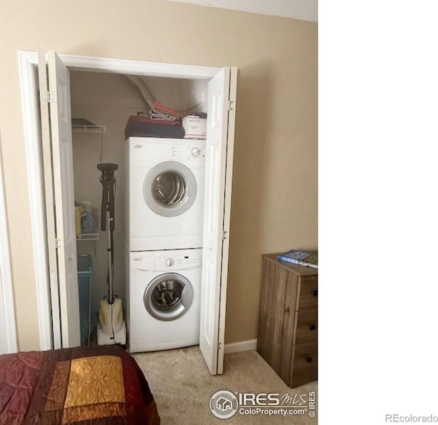 clothes washing area with light carpet and stacked washer and clothes dryer