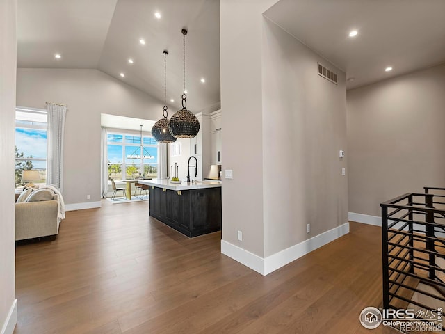 interior space featuring sink, wood-type flooring, decorative light fixtures, high vaulted ceiling, and white cabinets