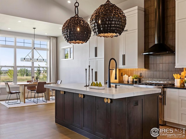 kitchen featuring plenty of natural light, decorative backsplash, wall chimney range hood, and stainless steel range