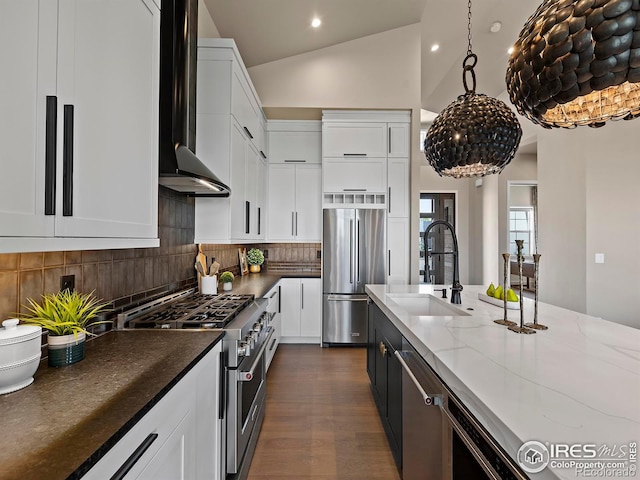 kitchen featuring premium appliances, white cabinetry, lofted ceiling, and sink