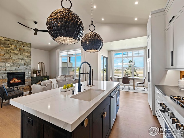 kitchen featuring a center island with sink, white cabinets, sink, and vaulted ceiling