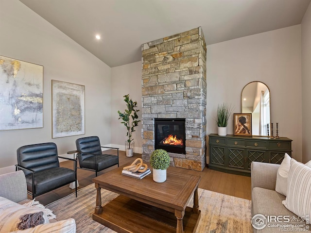 living room featuring a stone fireplace, lofted ceiling, and hardwood / wood-style flooring