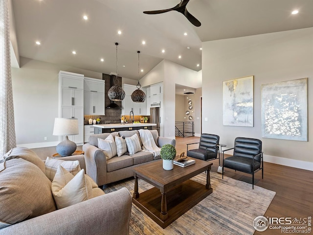 living room featuring ceiling fan, sink, high vaulted ceiling, and wood-type flooring