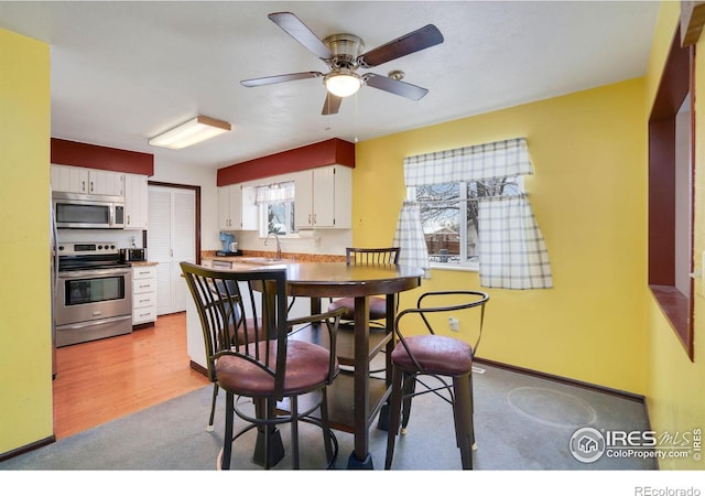 dining room with light carpet, ceiling fan, and sink