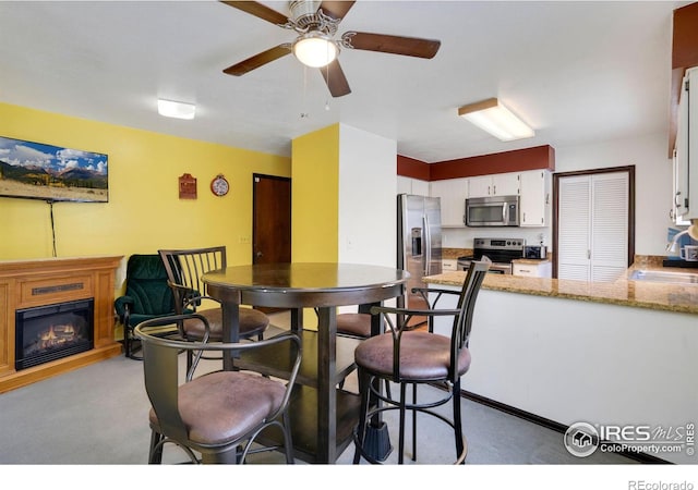 carpeted dining area with ceiling fan