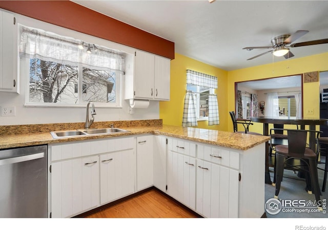 kitchen featuring white cabinets, sink, stainless steel dishwasher, ceiling fan, and kitchen peninsula