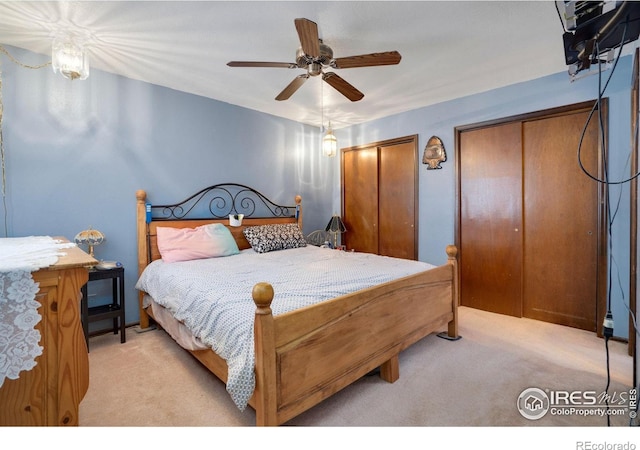 bedroom with light carpet, two closets, and ceiling fan