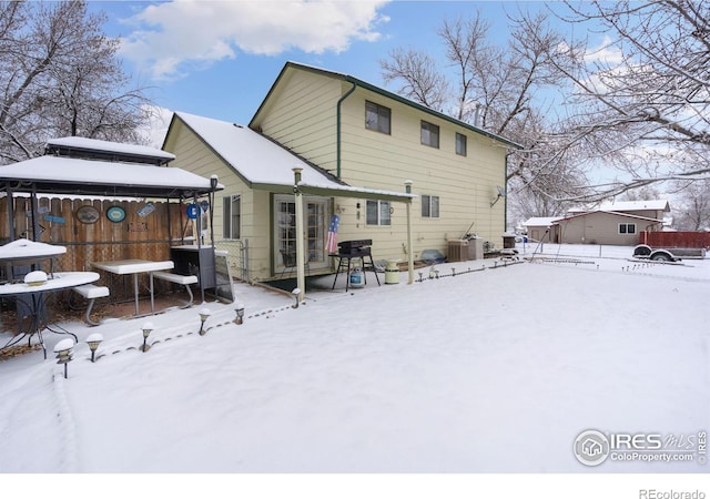 snow covered back of property featuring central AC unit