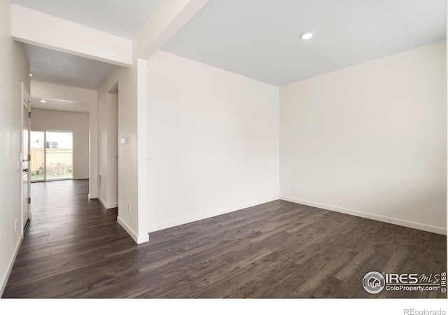 empty room with beam ceiling and dark wood-type flooring