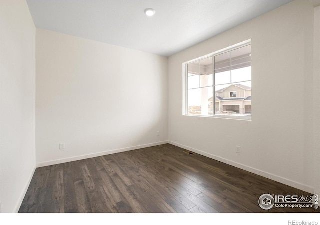 unfurnished room with dark wood-type flooring