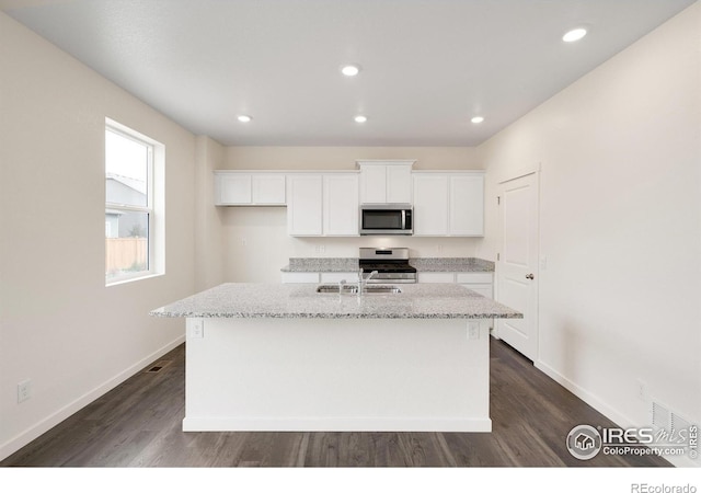 kitchen featuring light stone countertops, sink, a center island with sink, white cabinets, and appliances with stainless steel finishes