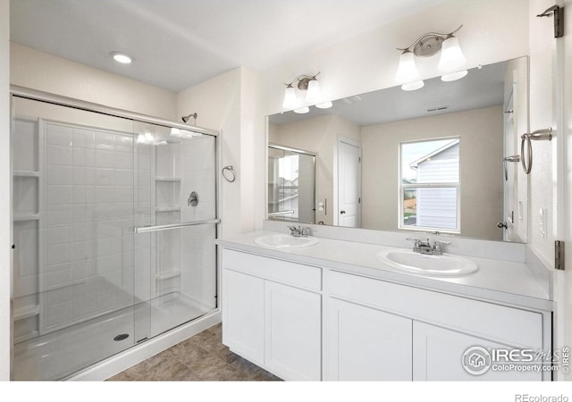 bathroom featuring a shower with door and vanity