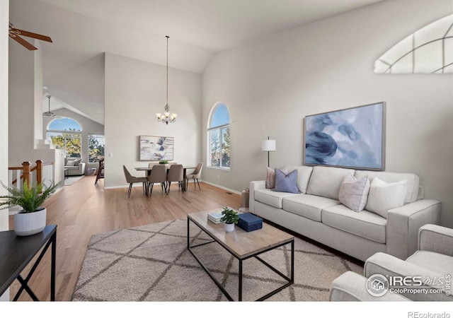 living room with hardwood / wood-style floors, ceiling fan with notable chandelier, plenty of natural light, and lofted ceiling