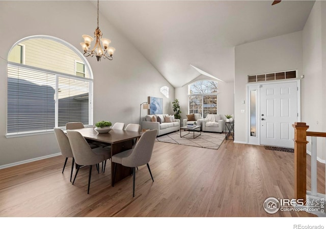 dining space with hardwood / wood-style floors, high vaulted ceiling, and an inviting chandelier