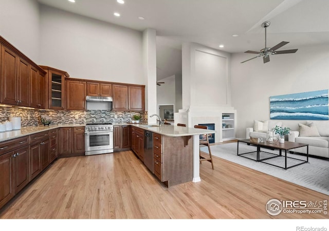 kitchen featuring sink, stainless steel appliances, high vaulted ceiling, kitchen peninsula, and a breakfast bar area