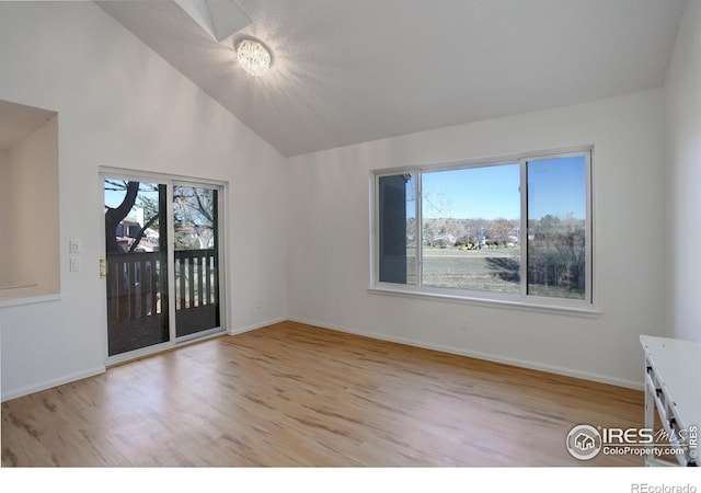 spare room featuring light wood-type flooring and vaulted ceiling