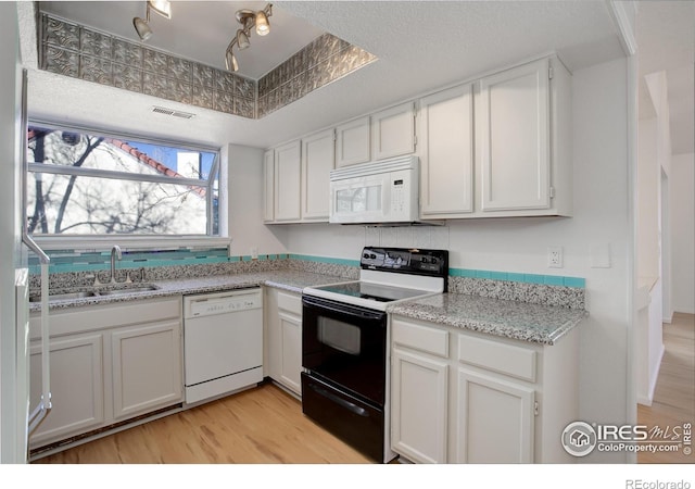 kitchen with light stone countertops, sink, white appliances, white cabinets, and light wood-type flooring