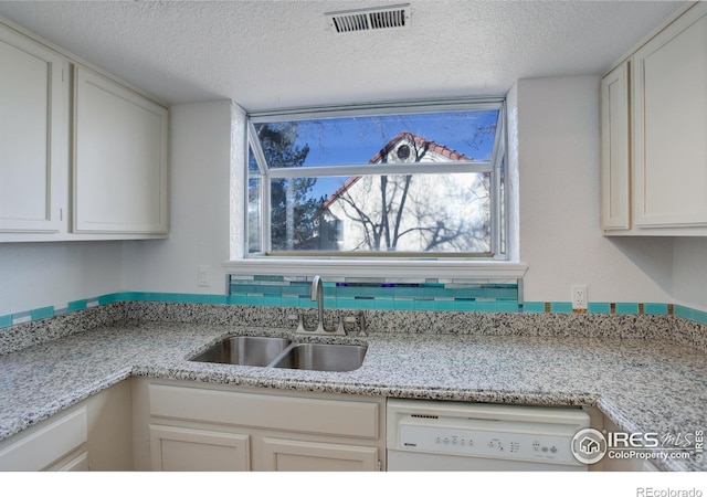 kitchen featuring dishwasher, sink, white cabinets, and a textured ceiling