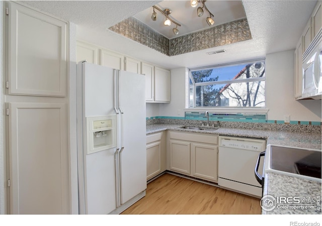 kitchen with white cabinets, white appliances, a raised ceiling, and sink