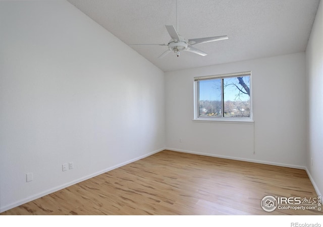 empty room with ceiling fan, vaulted ceiling, a textured ceiling, and light hardwood / wood-style flooring